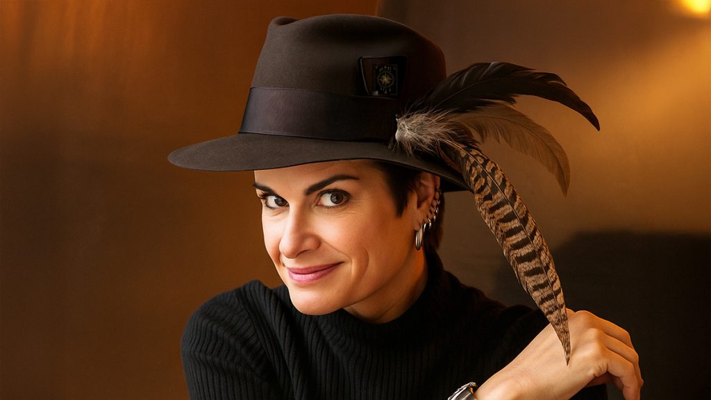 Avia sporting her hat with feathers and a tarot card