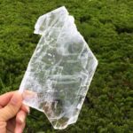 A woman holding a large crystal to show the spiritual benefits of selenite